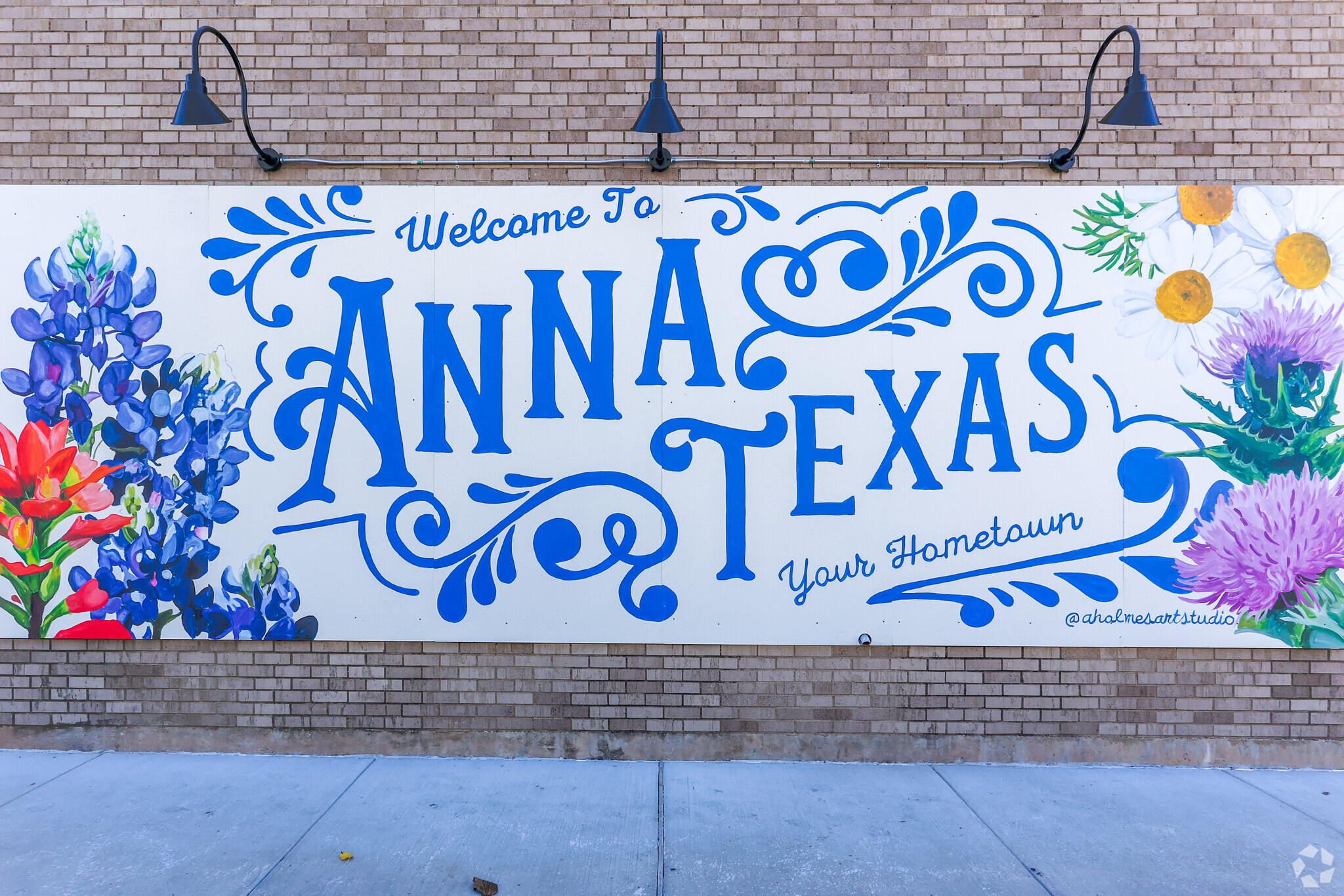 A mural reading 'Welcome to Anna, Texas — Your Hometown' painted with bluebonnets